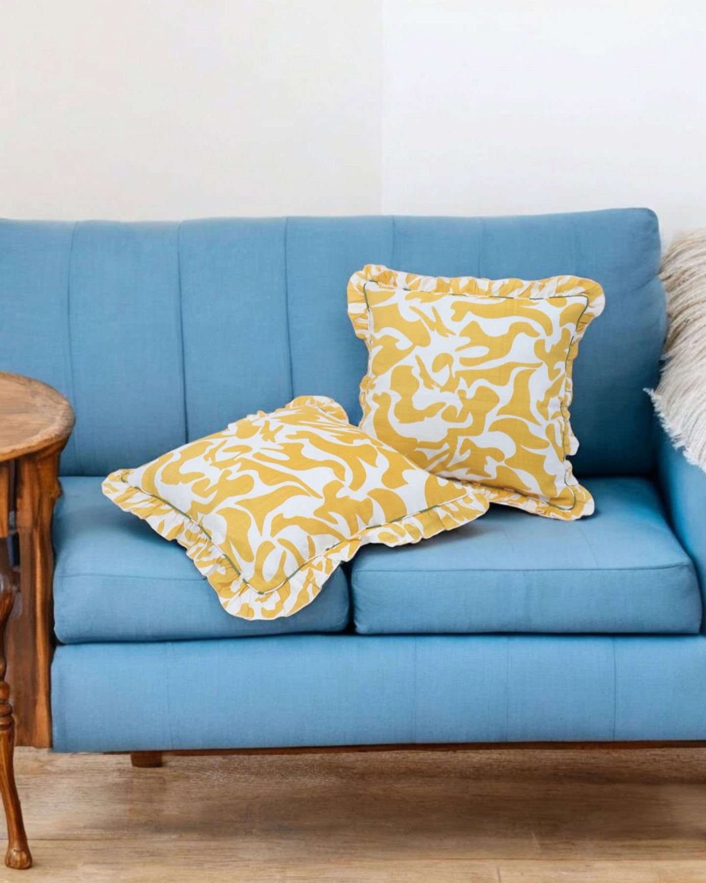 Yellow and white ruffled cushion covers on a blue sofa