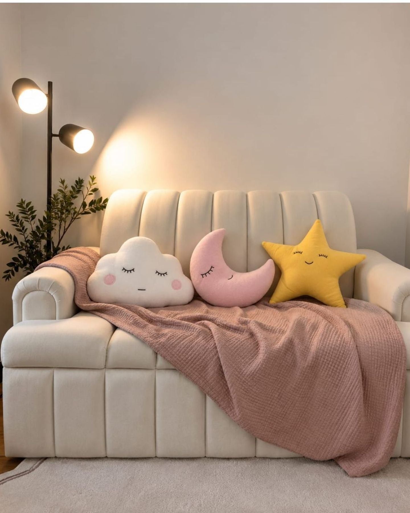 Moon, star and cloud cushions on a cream sofa with a pink throw